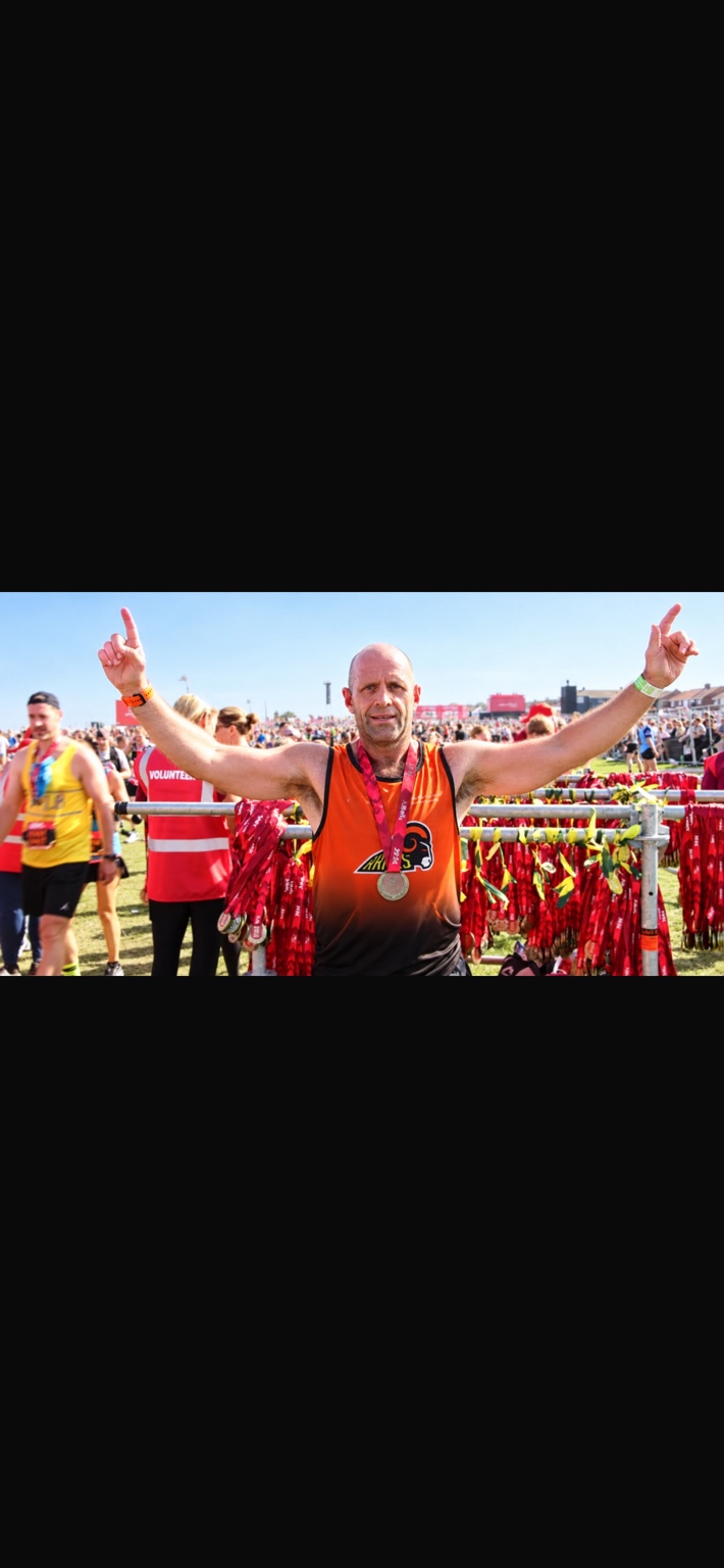 Kevin Richardson celebrating his Great North Run finish with his medal